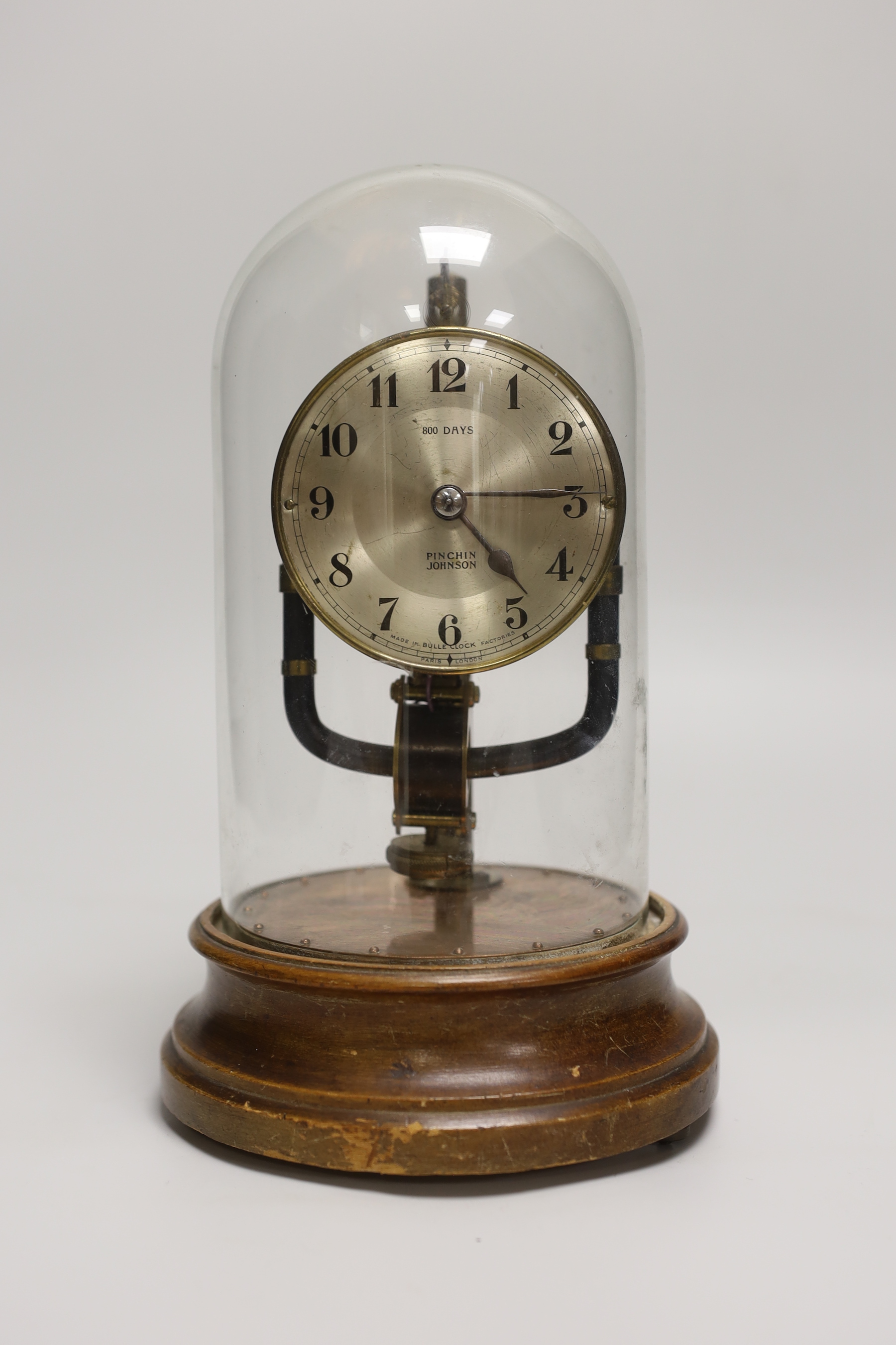 A Pinchin Johnson 800 day electric timepiece, under a glass dome, raised on a circular wood base, 26cm high